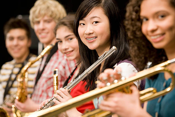 High-school girl playing flute with schoolmates